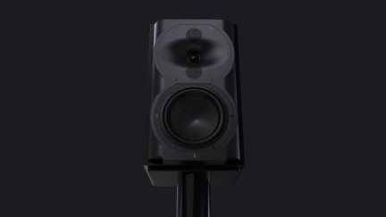 Altavoz negro visto de frente, 2 altavoces circulares, 1 tweeter central, caja rectangular, soporte cilíndrico vertical