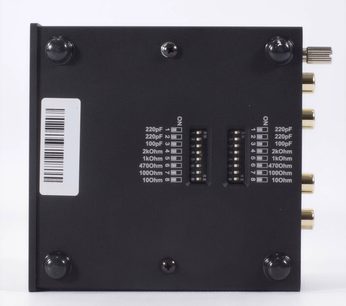 Pro-Ject Phono Box S2 phono-forforstærker sort, bagside, sort plan overflade, 4 cirkulære fødder, 2 DIP-switches, hvide inskriptioner, guldbelagte RCA-stik til højre, etiket med stregkode til venstre