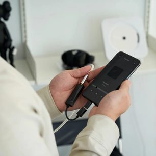 Håndholdt sort Astell&Kern AK HC3 bærbar audio-konverter set forfra, tilsluttet et hvidt kabel