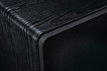 Subwoofer Alpha RS 8 v černé barvě s viditelnou texturovanou dřevěnou úpravou na zaobleném horním rohu a černou přední mřížkou