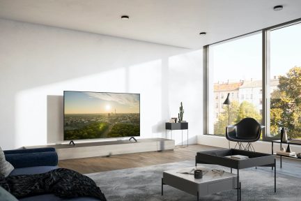 Moderne stue med fladskærms-tv, blå sofa, gråt sofabord, sort lænestol, stor panoramavindue