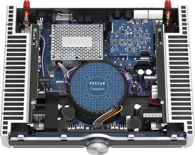 Integrovaný stereo hi-fi zesilovač Roksan CASPIAN 4G streaming v černé barvě, pohled shora na vnitřní část, elektronické obvody, centrální kruhový černý transformátor, postranní stříbrné chladiče, horní červené konektory, viditelné vícebarevné kabeláže