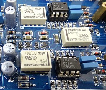 Modrý tištěný spoj s různými elektronickými součástkami, včetně čipů, rezistorů, kondenzátorů a konektorů