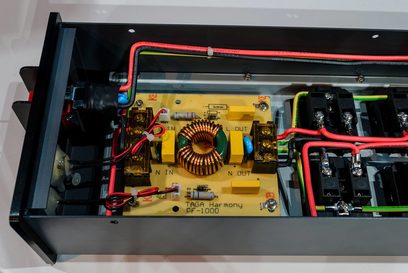 Multiprise Taga Harmony PF-1000 i sort, set forfra med åben indvendig visning af elektroniske komponenter og rød kabling