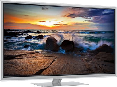 Tv-skærm, der viser en solnedgang over en klippestrand med store bølger og en farverig, skyet himmel