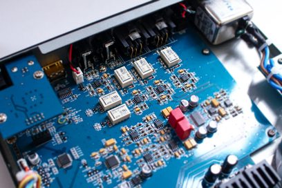 Blå printplade med elektroniske komponenter, transformere og audio-stik, tæt ovenfra-billede