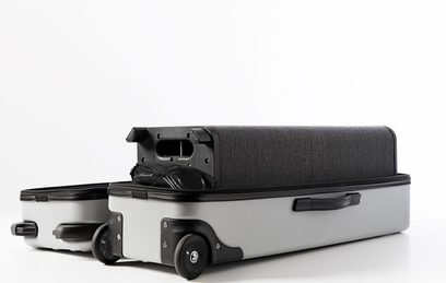 Grå og sort Escape P9 transportkuffert, set fra siden, med håndtag, hjul og rum til tilbehør