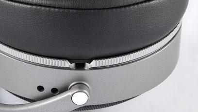 Nahaufnahme des schwarzen, lederstrukturierten Ohrpolsters, des matten grauen Metallgehäuses mit gerändeltem Ring und schwenkbarem Scharnier des geschlossenen, kabelgebundenen HiFi-Kopfhörers Audeze LCD-S20