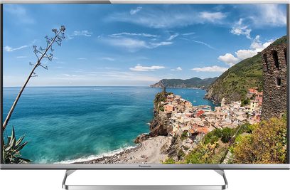 Televisore Panasonic TX-42AS650E che mostra un paesaggio costiero con un villaggio colorato, falesie e mare turchese sotto un cielo nuvoloso