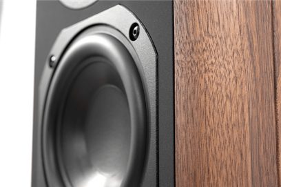 Hi-fi-højttaler i nærbillede fra trekvart vinkel, gråmetallic woofer fastgjort på mat sort baffel med synlige skruer, sidepanel i brun åretegnet træfinér