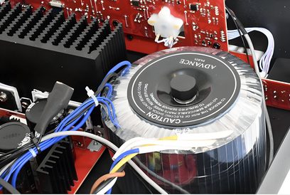 Hi-fi stereo zesilovač Advance Paris PlayStream A7, pohled shora s otevřeným krytem odhalujícím červené tištěné spoje a toroidní transformátor