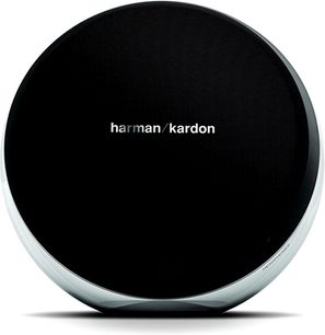 Enceinte compacte Harman Kardon, circulaire, noire, vue de face, posée sur une surface réfléchissante grise