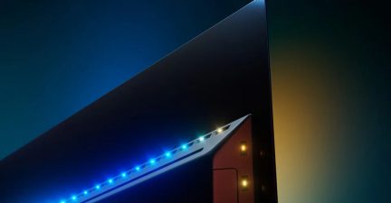 Close-up, three-quarter rear view from a low angle of the corner of a matte black metal flat screen, highlighted by a strip of blue and yellow LEDs