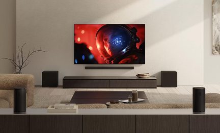 Sort hjemmebiografsystem med vægmonteret tv, soundbar og surroundhøjttalere i moderne stue