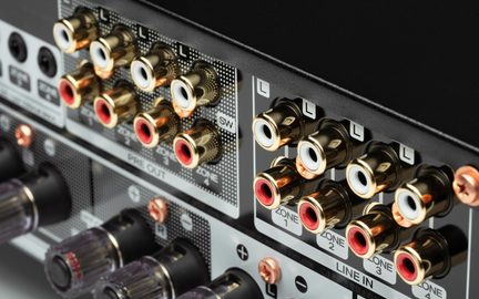Hi-fi stiprintuvo galinė panelė su keliais auksuotais raudonais ir baltais RCA garso lizdais, line įėjimais ir zonų išėjimais