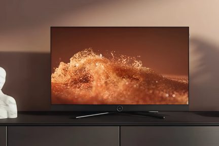 Zwarte flatscreen-tv met dunne rand op een laag meubel, abstract oranje beeld op het scherm, vooraanzicht