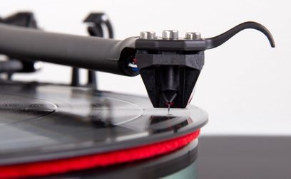Celula pick-up pentru viniluri Rega Ania Pro MC neagră, prim-plan din profil al brațului pick-up, cu focalizare pe vârful de citire roșu