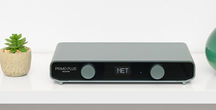 Lecteur réseau audio Volumio Primo Plus gris, façade noire à deux boutons et écran NET, posé sur étagère blanche