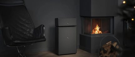 Dos cajas fuertes de color gris antracita de distintos tamaños, con cerradura central, junto a una chimenea encendida