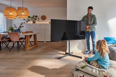 Moderne stue med en mand og en lille pige foran et stort fladskærms-TV monteret på en sort drejelig vægbeslag