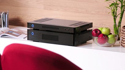 Frontansicht des schwarzen Rotel RB-1572 Stereo-Leistungsverstärkers mit zwei Knöpfen und Anschlüssen an der Vorderseite, auf einem Holztisch platziert
