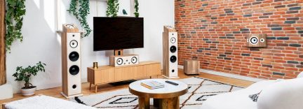 Soggiorno, vista frontale, sistema home cinema in legno chiaro con TV a parete, due colonne, centrale, subwoofer, diffusore a parete