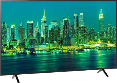 Panasonic TX-65LX700E fladskærms-TV viser et natligt vue af oplyste skyskrabere ved vandet, med en smal sort ramme