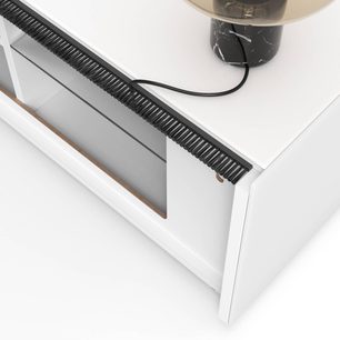 Bílý televizní nábytek s černou zásuvkou, černý kabel, černá lampa na bílé desce