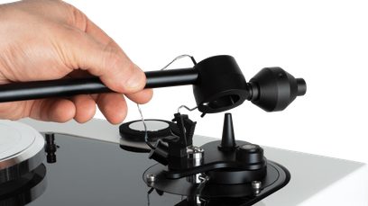 Tonearm til Roksan Sara sort pladespiller, nærbillede fra siden, hånd holder tonearmen over en vinylplade
