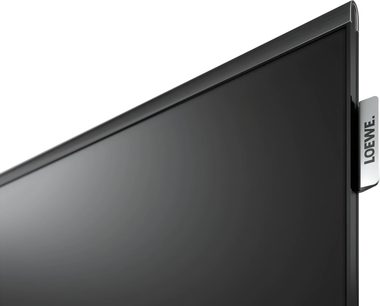 Loewe Antares 55 sort fjernsyn, nærbillede af skærmen og den sølvfarvede Loewe-sideplade