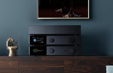 Na seba uložené čierne hi-fi zosilňovače s farebným displejom na drevenom TV stolíku v modernom obývacom priestore