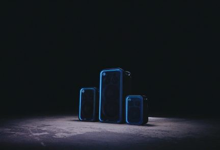Sorte bærbare Bluetooth-høyttalere med blå kanter, tre størrelser på mørk bakgrunn