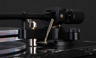 Czarna gramofon TEAC TN-550, zbliżenie z przodu na ramię tonowe z wkładką i przeciwwagą, na czarnej podstawce