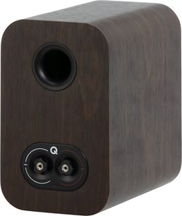 Knihovní reproduktor Q Acoustics 3010c v ořechovém provedení, skříň s tmavým dýhovým povrchem a zaoblenými hranami, pohled ze tří čtvrtin zezadu, s kruhovým černým basreflexovým výstupem a dvojitým stereo svorkovnicovým panelem