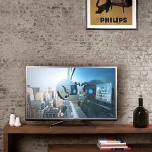 Philips 46PFL4528H-fladskærms-tv stillet på et træmøbel, der viser en futuristisk by, med to hvide vaser og en sort flaske