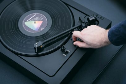 Platine vinyles hi-fi Pro-Ject A2 avec plateau circulaire noir, bras de lecture fin, bouton de commande et main ajustant un réglage