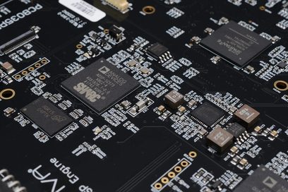 Sort printplade med mange rektangulære grå og guldfarvede elektroniske chips og elektroniske komponenter