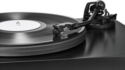 Gira-discos Audio Technica AT-LP7X preto com disco preto de rótulo branco e braço de leitura em close-up