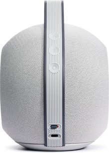 Портативна колонка Devialet Mania світло-сірого кольору, вид спереду, округлена циліндрична форма, сіра металева решітка, кнопки з боку
