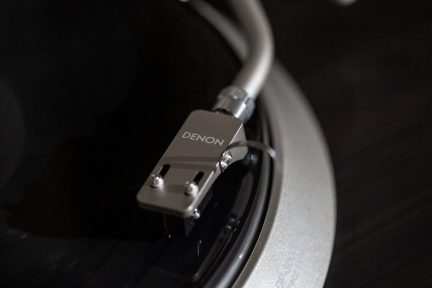 Testina di lettura del giradischi in vinile Denon con braccio in metallo e puntina di lettura, vista ravvicinata di profilo