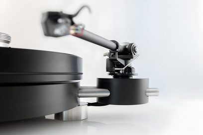 Nærbillede fra siden af Transrotor Max Nero RB220 hi-fi pladespiller i mat sort metal, med cylindrisk pladetallerken, rørformet tonearm og sølvfarvede aksler