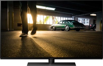 Televizor Panasonic TX-48MZ1500E zobrazující zelenou Oldsmobile Toronado zaparkovanou v krytém parkovišti, pohled zezadu z boku