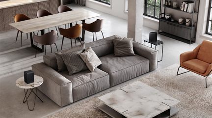 Draufsicht auf ein modernes Wohnzimmer: Niedriges Sofa aus grauem Stoff mit breiten Armlehnen, zwei kompakte schwarze Lautsprecher mit geriffelter Front auf filigranen Beistelltischen mit Metallgestell und heller Marmorplatte, rechteckiger Couchtisch in Marmoroptik und cognacfarbener Ledersessel.