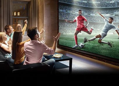 Videoprojektor Sony VPL-XW7000ES v bílé barvě promítá fotbalový zápas na plátno, zatímco rodina sleduje z pohovky.