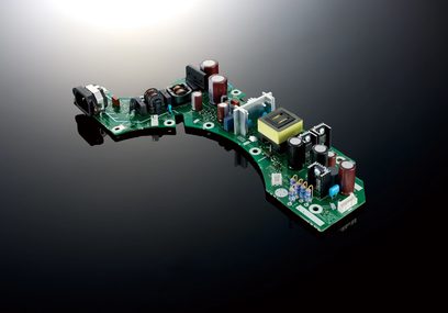 Žalia spausdintinė plokštė su įvairiais elektroniniais komponentais, įskaitant kondensatorius ir transformatorius