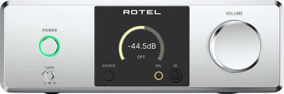 Rotel Dx-3 high-fidelity hovedtelefonforforstærker i sølvfarvet aluminium, set forfra, rektangulær front med sort centralt display med digital måler, cirkulær tænd/sluk-knap med grøn ring og tretrins gain-vælger til venstre, stor metalvolumenknap til højre