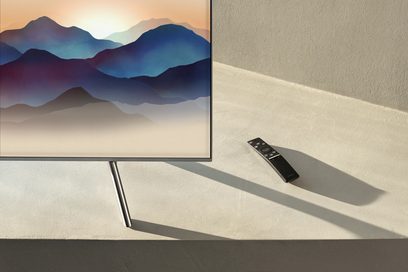Samsung QE65Q6F 2018 fladskærms-TV, der viser et abstrakt bjerglandskab i blå og beige nuancer på en ensfarvet beige baggrund