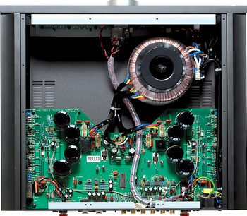 Indvendigt billede af en sort Musical Fidelity M6i stereo hi-fi forstærker, der viser en toroidaltransformer og elektroniske kredsløb