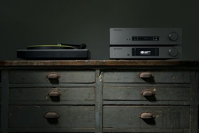 Cambridge Audio CXA61 stereo hi-fi forstærker i antracitgrå, sølvfarvet finish, stående på et patineret trækabinet, set forfra