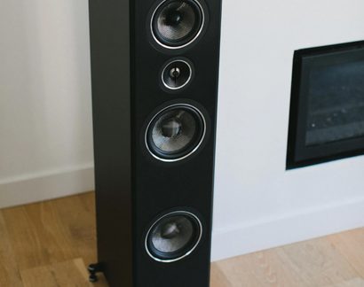 Zwarte kolomluidspreker, mat houten behuizing, centrale tweeter en 3 woofers met geweven conussen, driekwarts zicht